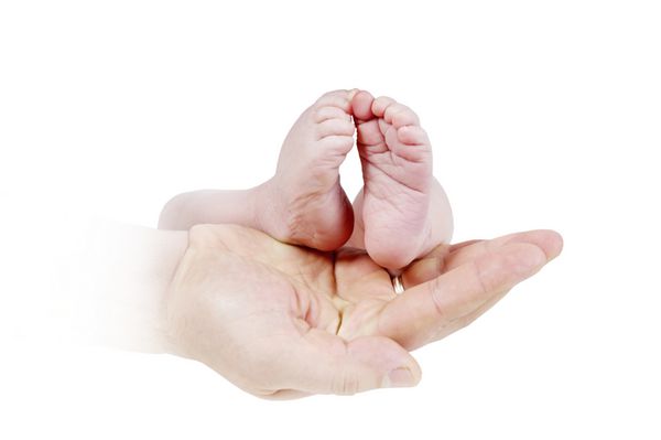 پای نوزاد در دستان پدر در زمینه تک رنگ