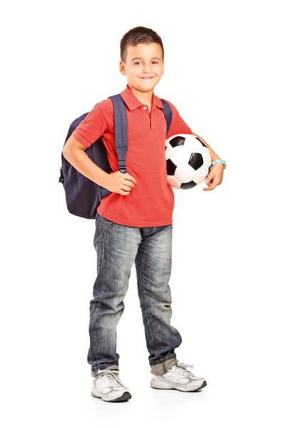 پرتره تمام قد کودک با کوله پشتی که توپ فوتبال را در پس زمینه سفید در دست دارد