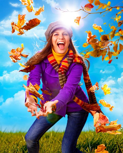 دختری که در یک روز پاییزی برگ پرتاب می کند