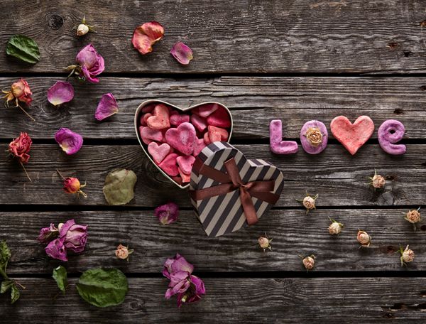 Word Love با جعبه هدیه روز ولنتاین به شکل قلب روی بشقاب های چوبی قدیمی پس زمینه شیرین تعطیلات با گلبرگ های رز و گل های رز خشک شده