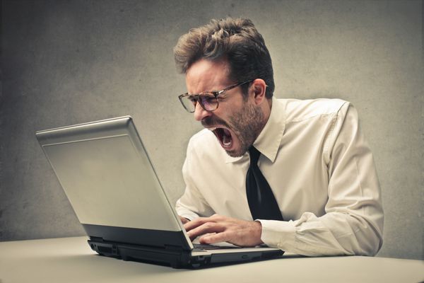 تاجر عصبانی که روی لپ تاپ کار می کند