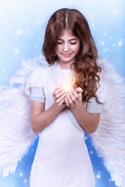 فرشته کریسمس ناز در زمینه آبی برفی دختر شایان ستایش با شمع در دست تعطیلات مذهبی زمستانی مفهوم صلح و هماهنگی