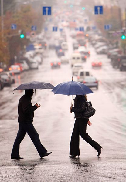 مردم شهری زیر باران از خیابان عبور می کنند