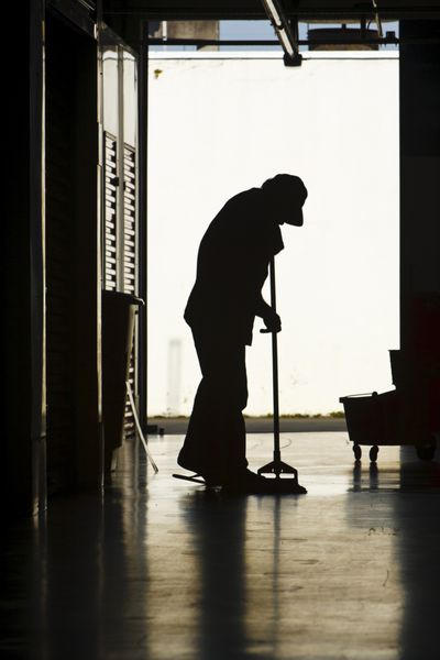 سیلوئت مردی که کف انبار را تمیز می کند