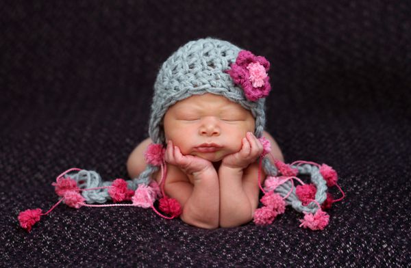 نوزاد زیبای تازه متولد شده که روی آرنج و دستانش تکیه داده است