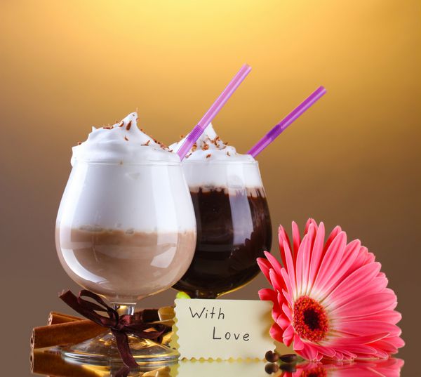 لیوان های کوکتل قهوه و گل ژربرا در زمینه قهوه ای
