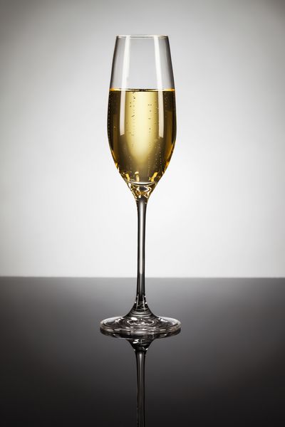 لیوان شامپاین روی آینه با نقطه در پس زمینه