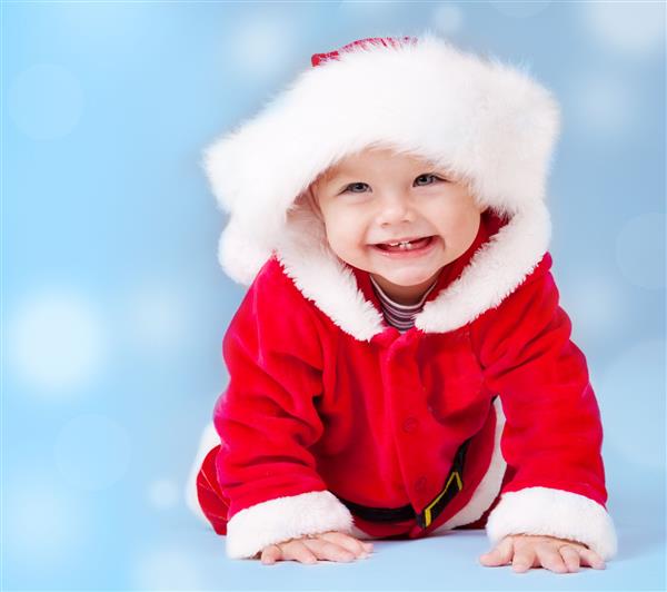 کودک شیرین با لباس بابانوئل روی پس‌زمینه آبی با کپی‌اسپیس