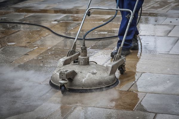 کارگر در حال تمیز کردن یک پیاده‌رو در آکسفورد انگلستان با بخار