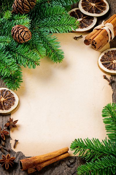 قاب با کاغذ پرنعمت و شاخه های درخت کریسمس در زمینه چوبی