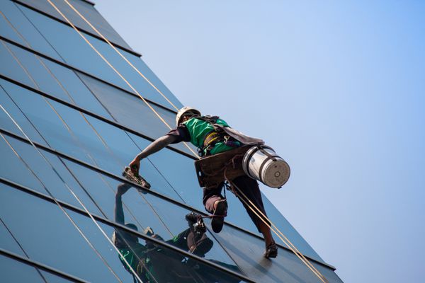 گروهی از کارگران در حال تمیز کردن پنجره ها در ساختمان های مرتفع