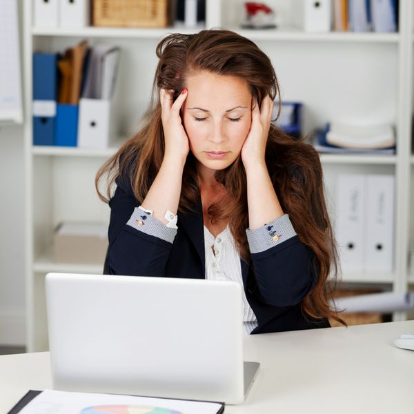 زن ناراضی که در دفترش با چشمان بسته و دستانش به سرش نشسته است یا به خاطر حالش خوب نیست یا به دلیل استرس و ناامیدی در کارش