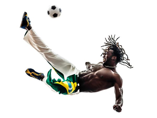 یک بازیکن فوتبال مرد سیاهپوست برزیلی در حال لگد زدن به فوتبال در پس زمینه سفید