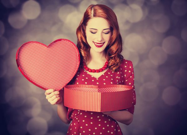 دختر مو قرمز با هدیه برای روز ولنتاین عکس با بوکه در پس زمینه
