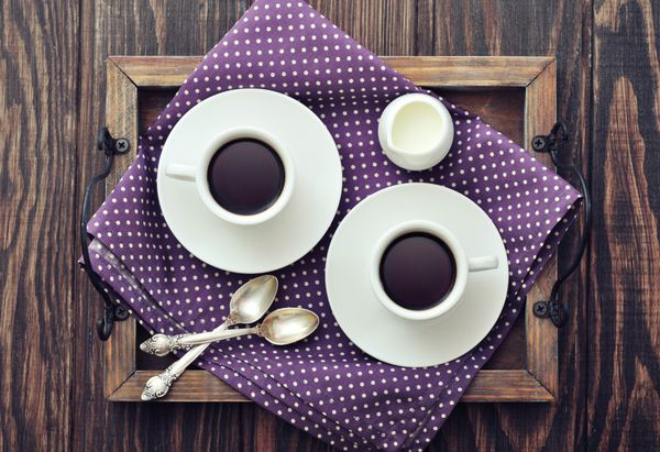 قهوه در فنجان با قاشق و شیر روی سینی چوبی قدیمی