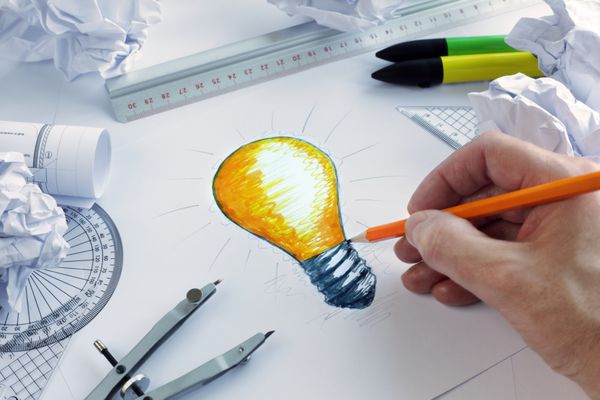 طراح در حال کشیدن یک لامپ مفهومی برای طوفان فکری و الهام گرفتن