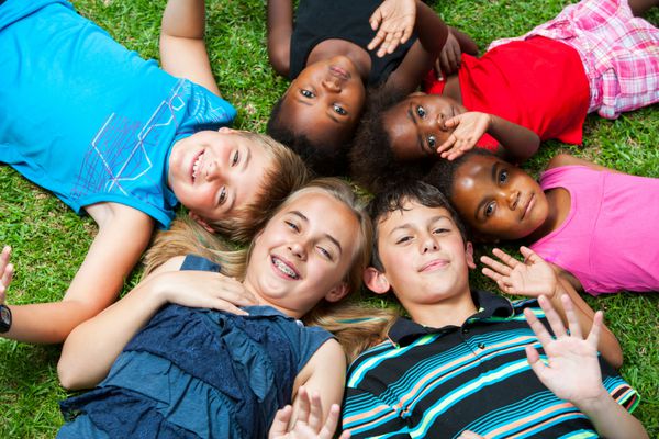 گروه چند نژادی متنوع از بچه ها که سرها را به هم می چسبانند