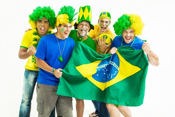 گروهی از هواداران شاد برزیلی با لباس های سبز زرد و آبی پرچم برزیل را در دست دارند