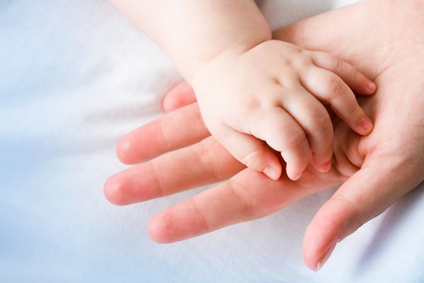 تصویر کف دست مادر با دست نوزاد تازه متولد شده روی سطح آن