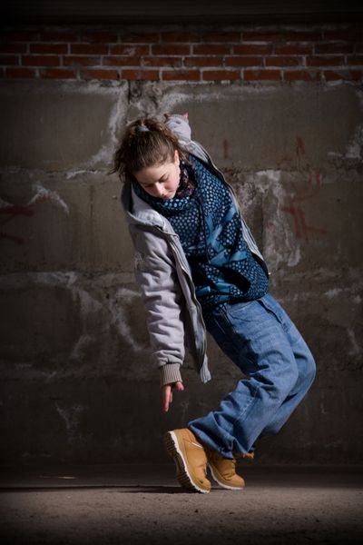 رقص دختر هیپ هاپ به سبک مدرن بر روی دیوار آجری خاکستری شهری