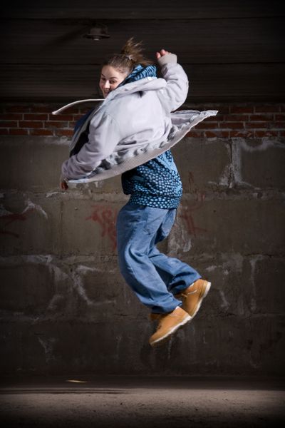 رقص دختر هیپ هاپ به سبک مدرن بر روی دیوار آجری خاکستری شهری