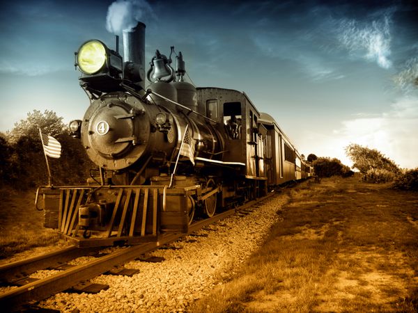 قطار لوکوموتیو موتور بخار قدیمی در حال حرکت در مسیر راه آهن به سمت دوربین پرچم های آمریکا در جلو عکس سیاه و سفید نقاشی شده با دست