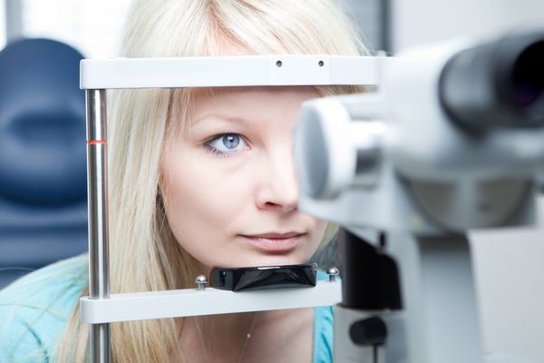 مفهوم بینایی سنجی - زن جوان زیبایی که چشم هایش را توسط چشم پزشک روی یک لامپ شکاف معاینه می کند