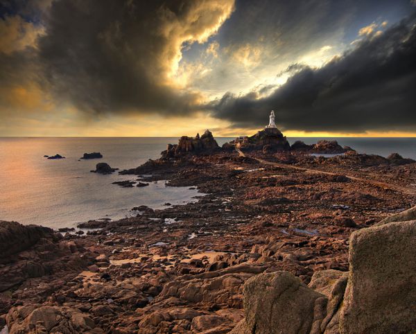 فانوس دریایی La Corbiere در جزیره جرسی انگلستان انگلستان با یک آسمان دراماتیک در پس زمینه