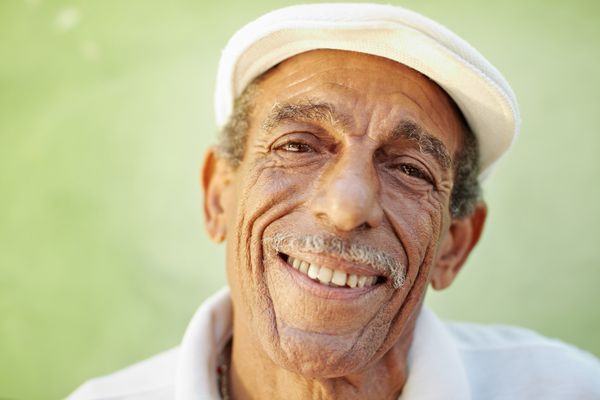 پرتره مرد اسپانیایی تبار با کلاه سفید که به دوربین مقابل دیوار سبز نگاه می کند و لبخند می زند شکل افقی فضای کپی