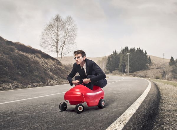 تاجر جوان در حال رانندگی یک ماشین اسباب بازی در یک جاده روستایی