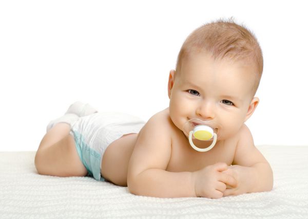 نوزاد کوچک بسیار زیبا روی شکم دراز کشیده روی زمینه سفید جدا شده