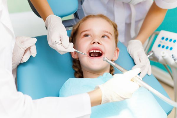 دختر کوچکی که در مطب دندانپزشکی نشسته است