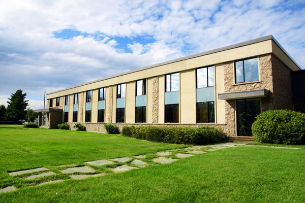 نمای ساختمان اداری یا تجاری کوچک یا مدرسه کالج با آسمان و چمن عکس گرفته شده است