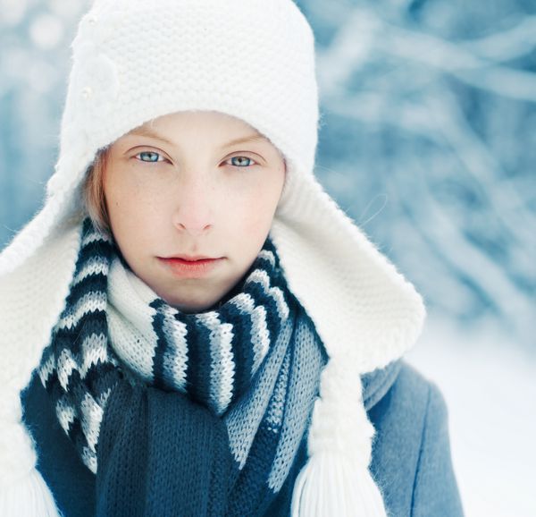 دختر زیبای شادی که در زمستان در پارک کلاه گرمی به تن دارد پرتره با رنگ های آبی سرد