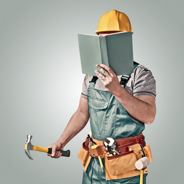 کارگر ساختمانی با تسمه ابزار و کتاب