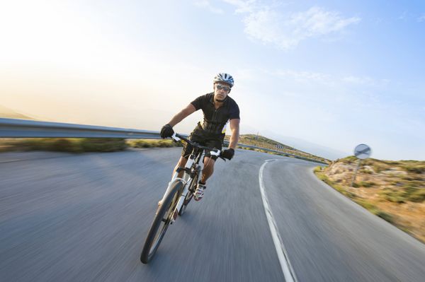 مرد دوچرخه سوار دوچرخه سواری کوهستان در روز آفتابی در جاده کوهستانی