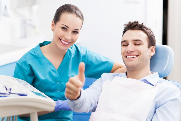 مردی که در مطب دندانپزشکی شست را بالا می‌گیرد