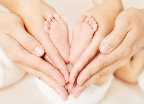 پاهای نوزادی که والدین در دست گرفته اند نوع تازه متولد شده و نماد عشق به عنوان علامت قلب