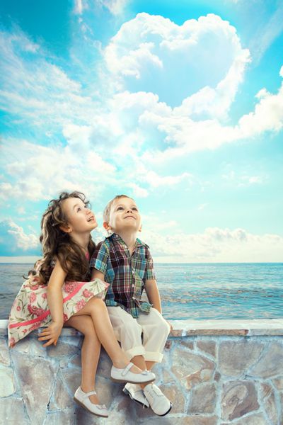 کودکان شاد با ابرهای قلبی شکل به آسمان آبی نگاه می کنند مردم مفهوم شادی