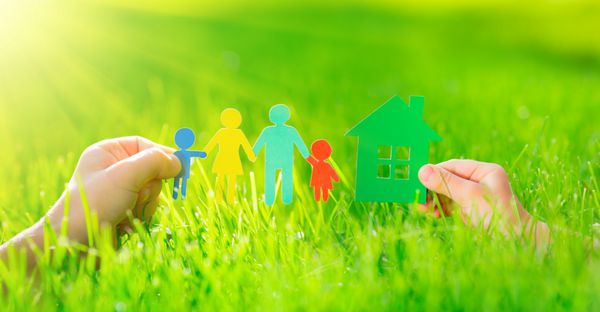 خانه کاغذی و خانواده در دست روی چمن سبز بهاری مفهوم اکولوژی