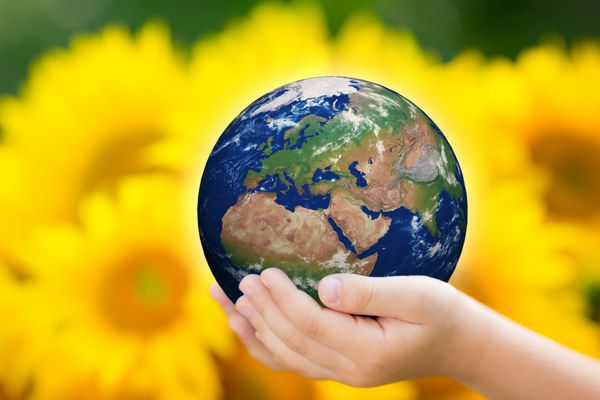 کودکی که زمین را در دستانش در پس زمینه سبز بهار گرفته است عناصر این تصویر توسط ناسا ارائه شده است
