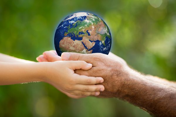 کودک و مرد سالخورده ای که زمین را در دستان خود در برابر پس زمینه سبز بهار گرفته است عناصر این تصویر توسط ناسا ارائه شده است