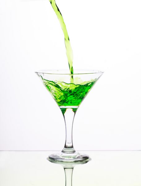 کوکتل الکل سبز در لیوان مارتینی با چلپ چلوپ در پس زمینه سفید
