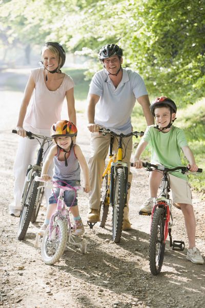 خانواده ای که روی دوچرخه در مسیر نشسته و لبخند می زنند