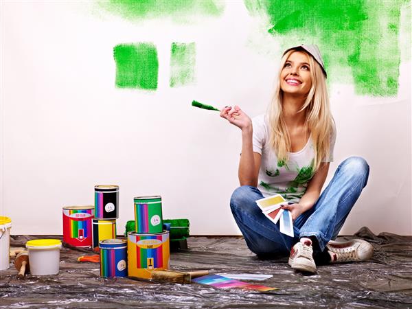 زن شاد دیوار خانه را رنگ می کند