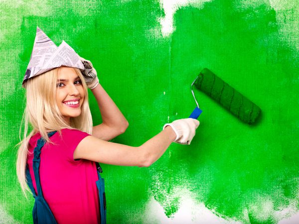 زن شاد دیوار خانه را رنگ می کند