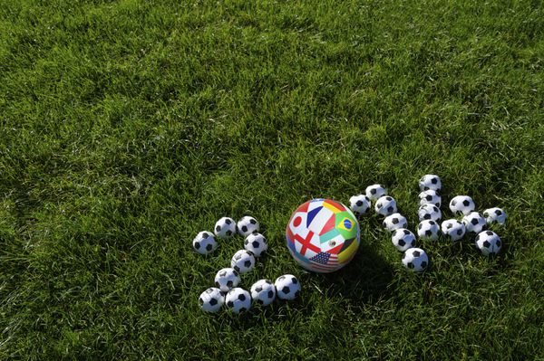 پیام سال 2014 با توپ های فوتبال تیم های بین المللی در زمین چمن سبز