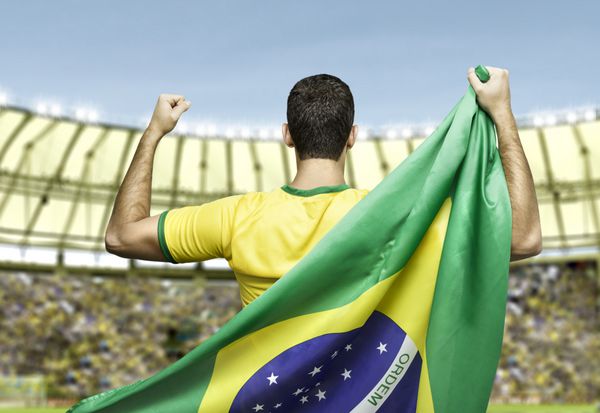 فوتبالیست برزیلی که پرچم برزیل را در دست دارد در ورزشگاه جشن می گیرد