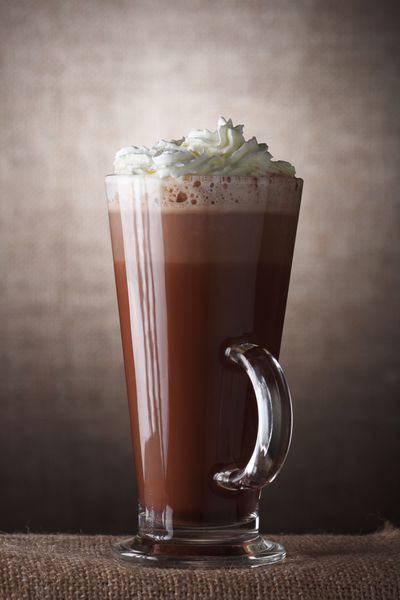 شکلات داغ با خامه در شیشه بلند در زمینه قهوه ای روستایی تکنیک نورپردازی کم کلید