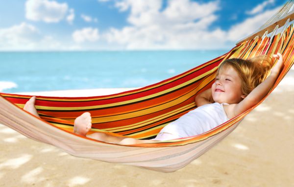 کودک در حال استراحت در یک بانوج در ساحل دریا